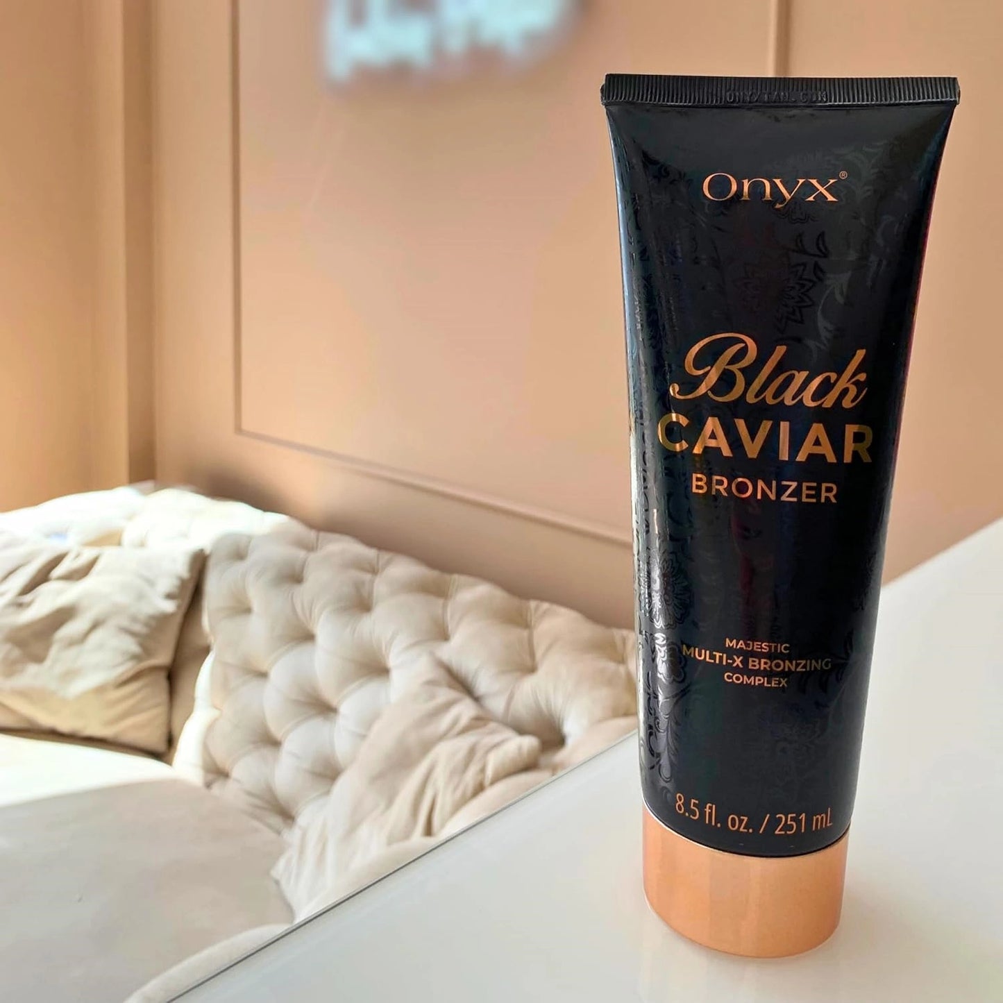 Loción bronceadora Onyx Black Caviar 251 ml sobre una superficie blanca frente a un sofá acogedor en una habitación luminosa