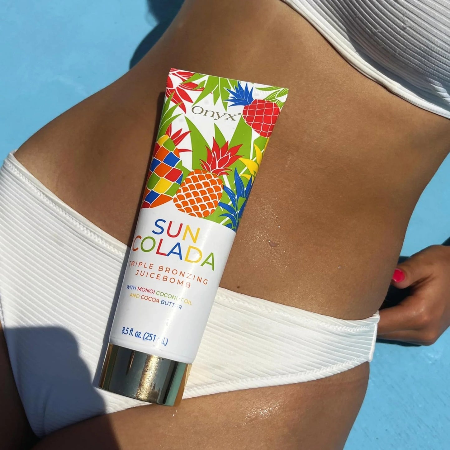 Suncolada loción bronceadora sobre abdomen bronceado con fondo azul
