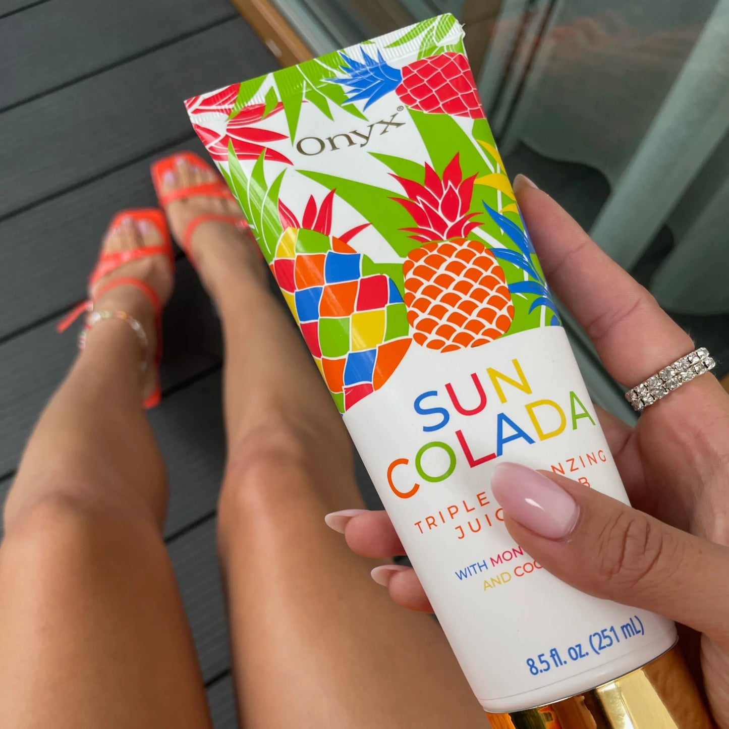 Enfoque en Suncolada loción bronceadora con zapatos rojos en el fondo
