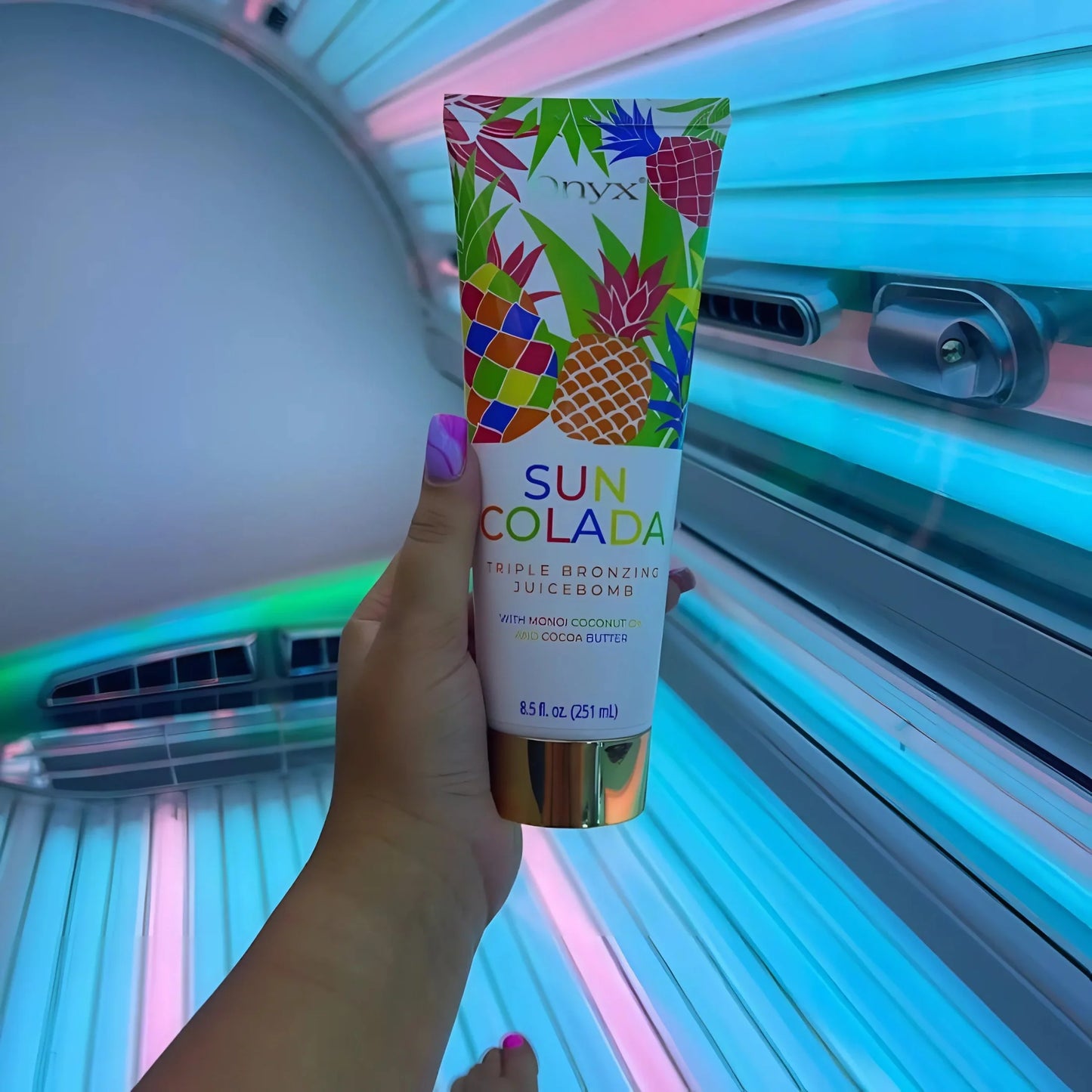 Suncolada loción bronceadora sostenida verticalmente en la mano en el solárium
