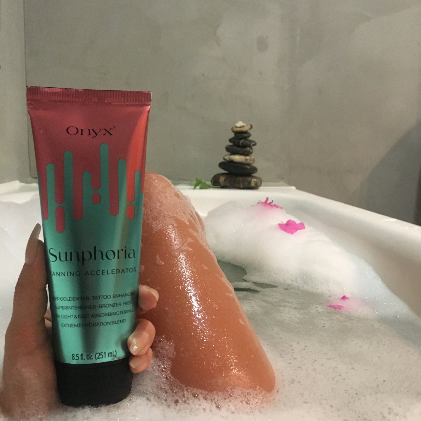 Onyx Sunphoria sunbed tanning accelerator cream in hand while relaxing in bath with tan legs