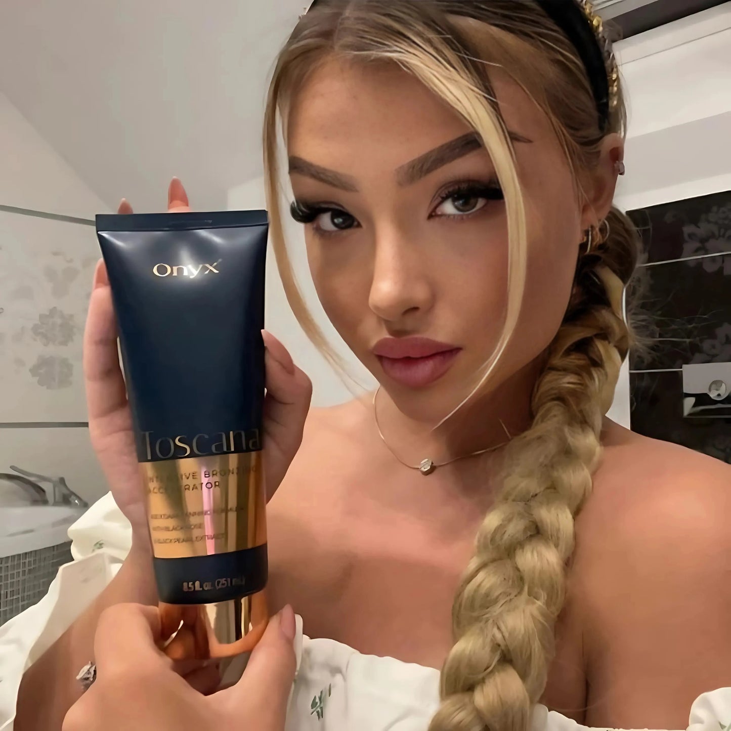 Mujer rubia con trenza sostiene la loción bronceadora Toscana en un baño