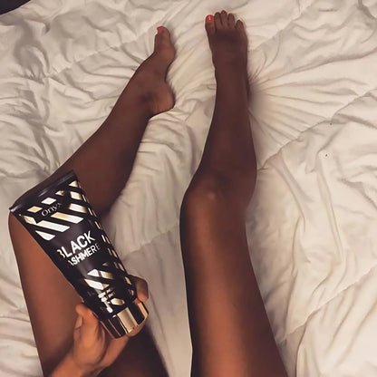 Piernas bronceadas sobre manta blanca con loción en la mano