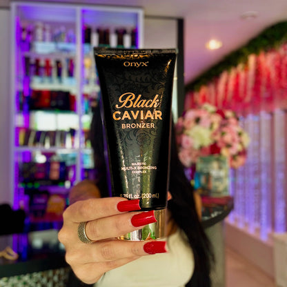 Mujer con uñas rojas sostiene la loción bronceadora Onyx Black Caviar 251 ml frente a la cámara en una sala con estantes de cosméticos