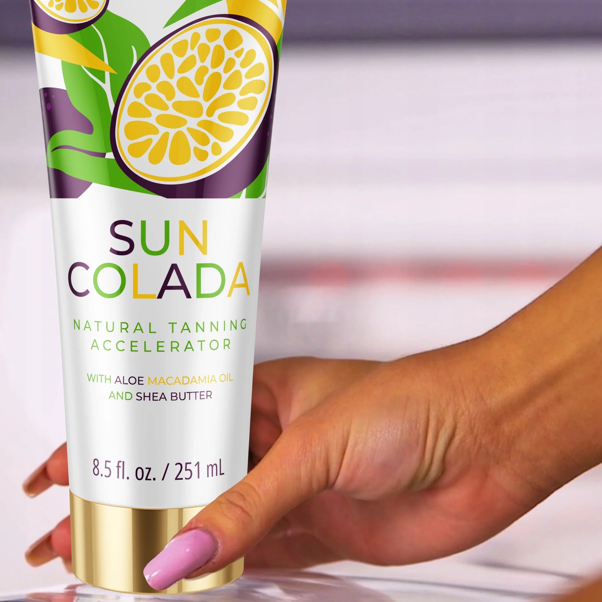 Dłoń trzymająca balsam do opalania Onyx Suncolada w białym i złotym opakowaniu, wzbogacony masłem shea i olejem makadamia, jako ultra nawilżający przyspieszacz opalania