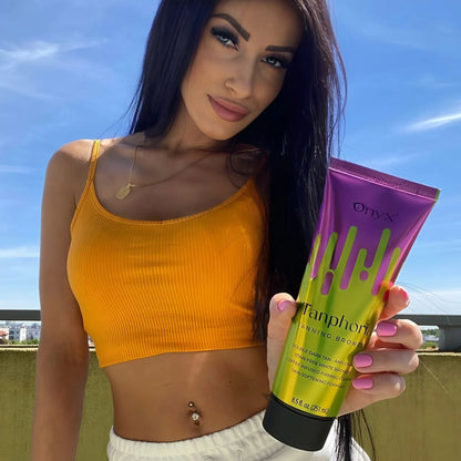 Mujer con cabello negro largo sostiene Tanphoria bronceador bajo cielo azul